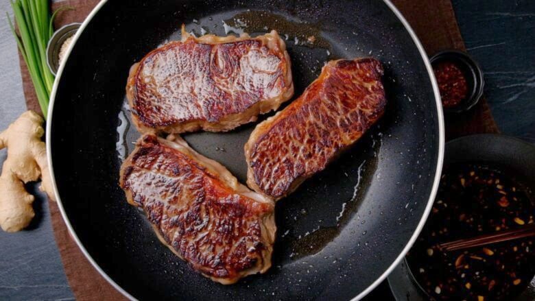 steaks cooking in pan on second side.