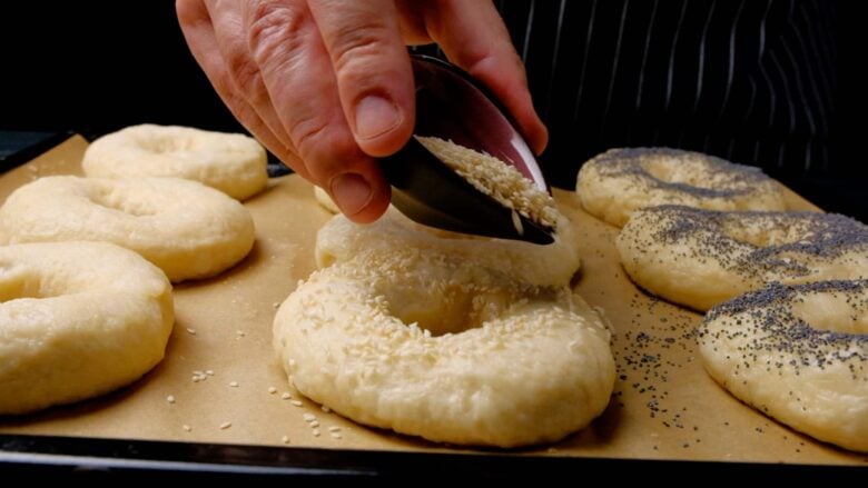Bagels Being Sprinkled with Toppings.