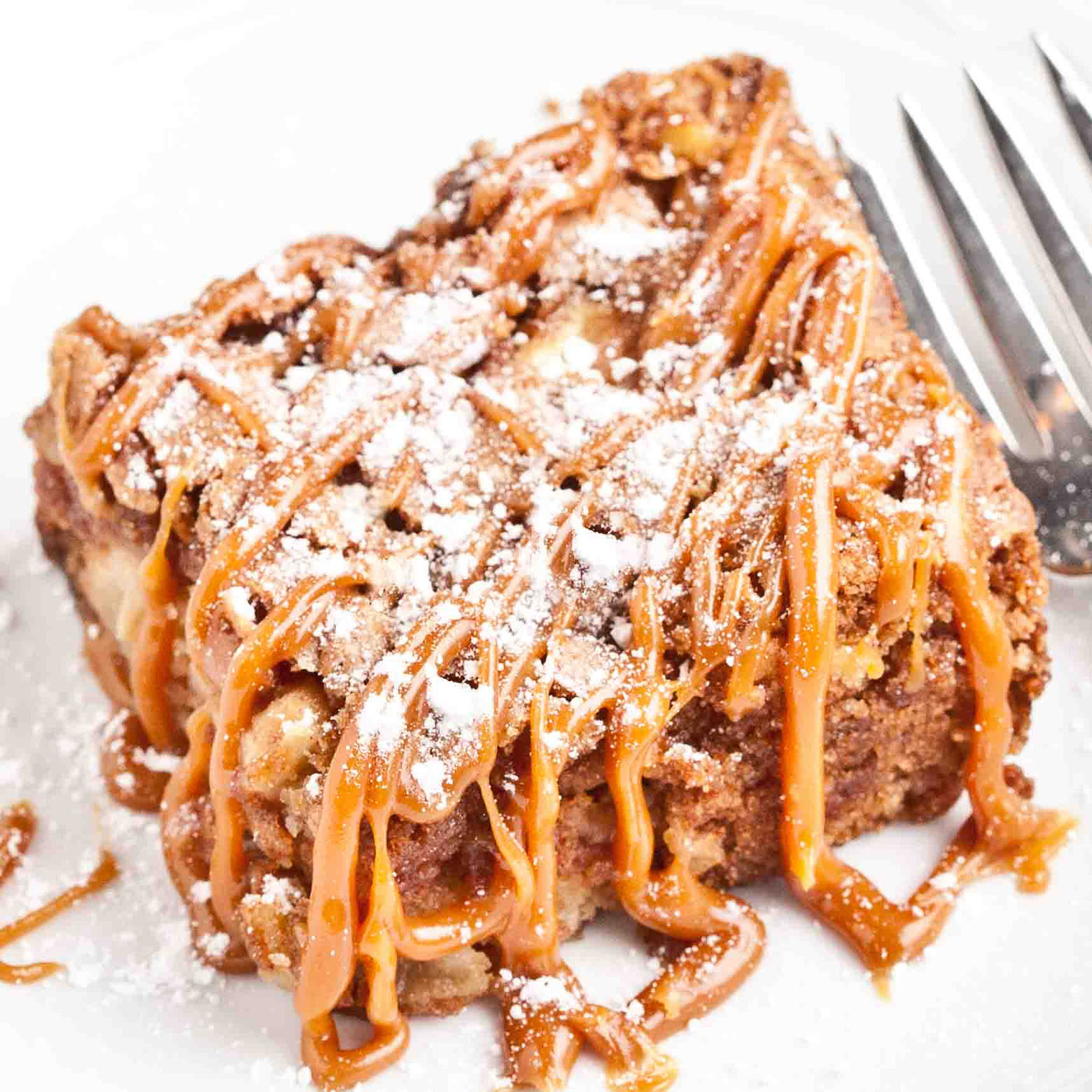 Close up of a slice of apple cake with lots of caramel drizzle. 