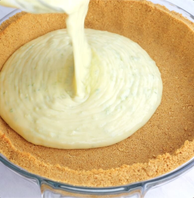 key lime pie filling being poured into graham cracker crust