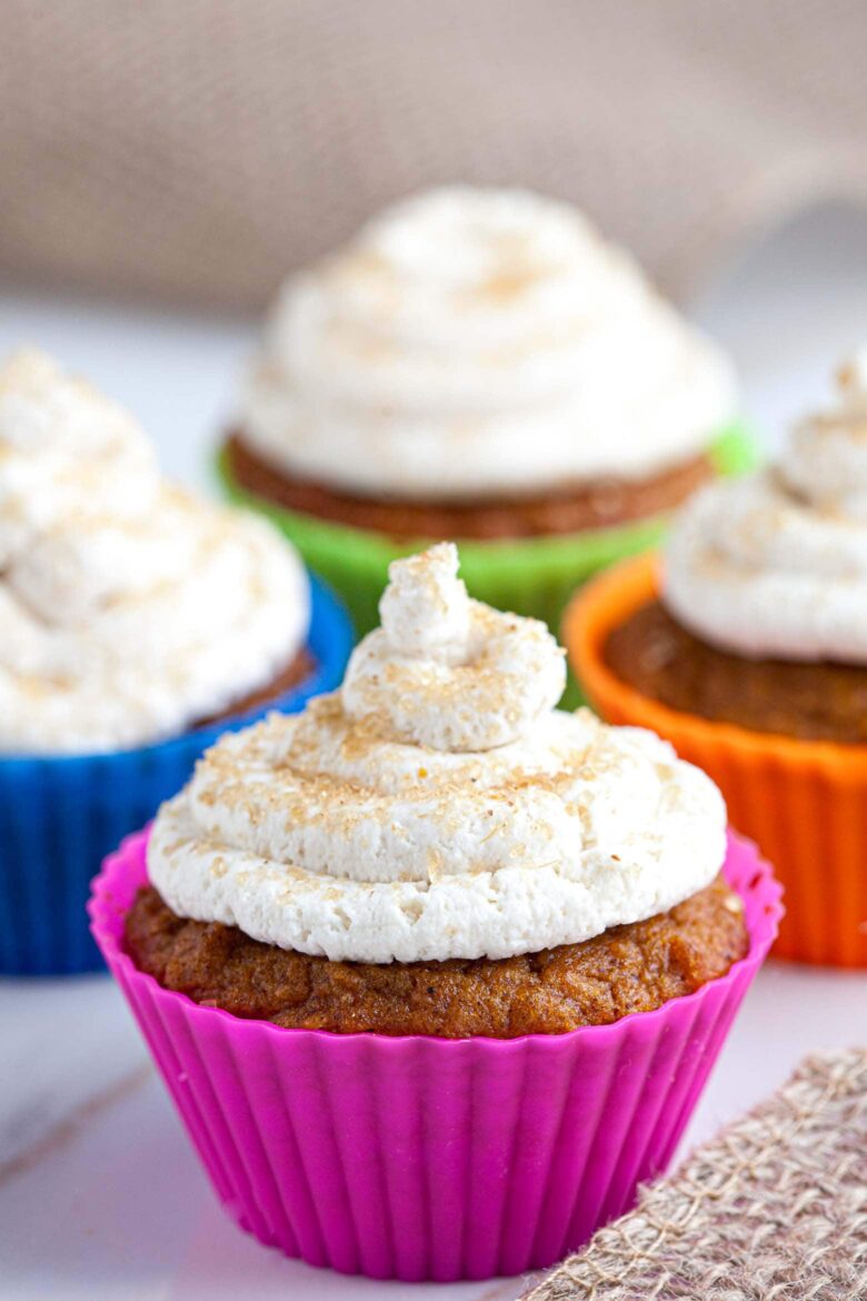 Pumpkin Cupcakes with whipped cream frosting in colorful cups.