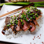 Beef Teriyaki sliced on a bed of white rice with green onions