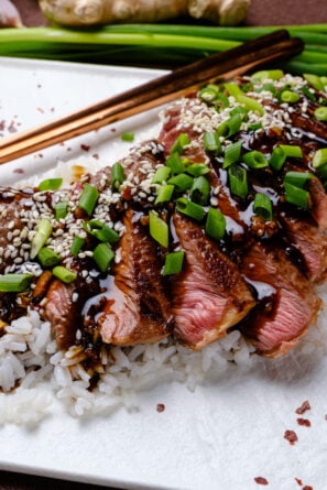 Beef Teriyaki sliced on a bed of white rice with green onions.