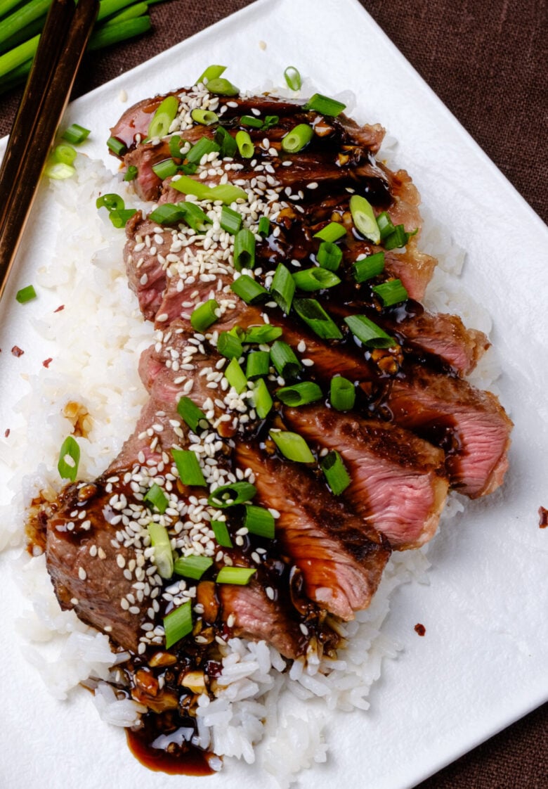 Beef Teriyaki sliced on a bed of white rice with green onions,