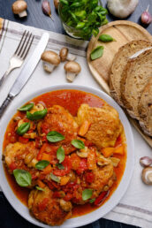 Overhead shot of chicken cacciatore on a plate with bread on the side.