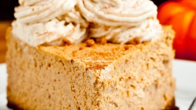 Slice of pumpkin cheesecake with whipped cream topping.