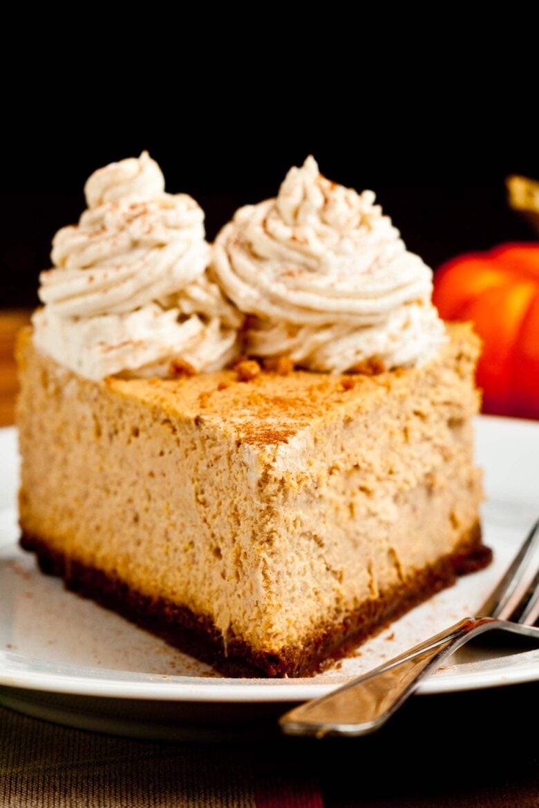 Slice of pumpkin cheesecake with whipped cream topping.