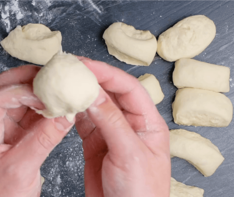 Easy dinner roll dough being shaped into round balls. 