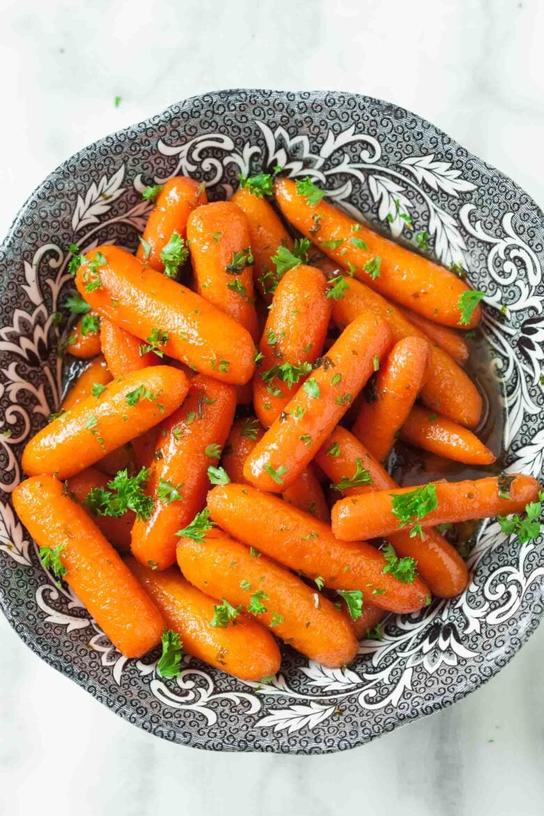Honey glazed carrots garnished with parsley in a bowl.