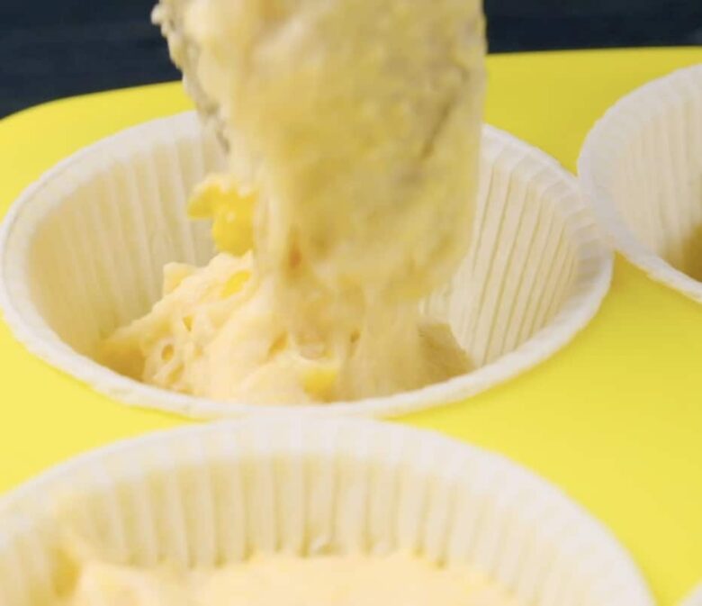 honey cornbread muffins being scooped into muffin tins.