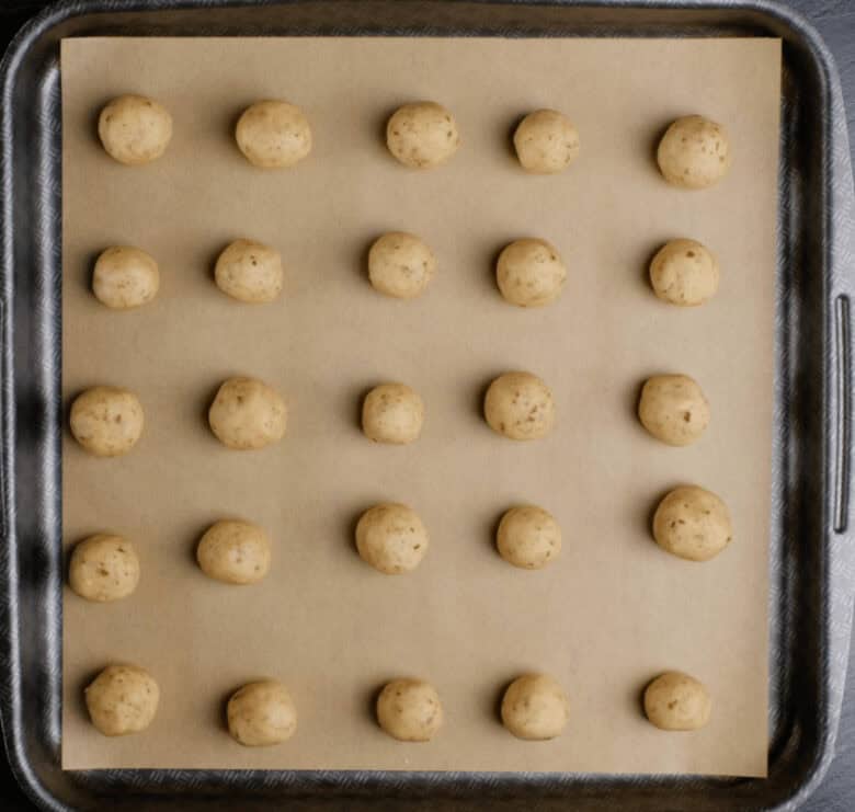 snowball cookie dough rounds on baking sheet.