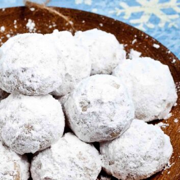 snowball cookies stacked on a plate.