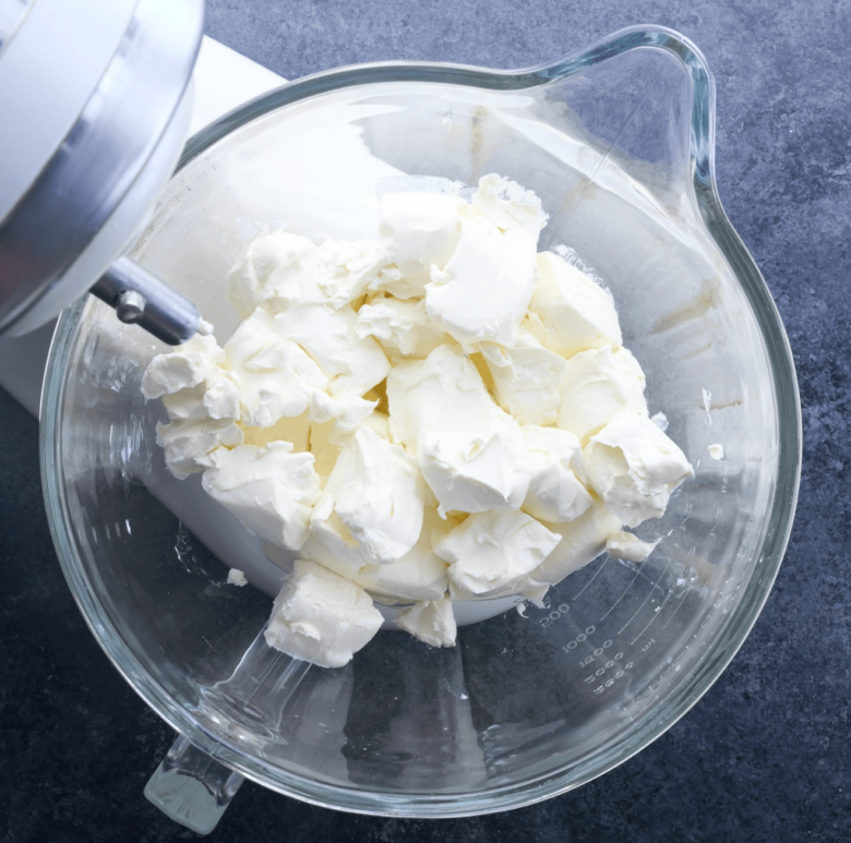 Cream cheese in the bowl of a stand mixer.