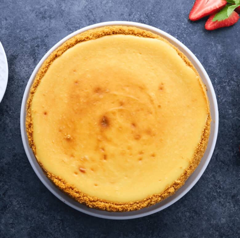 Overhead shot of a fully baked New York style cheesecake on a plate.