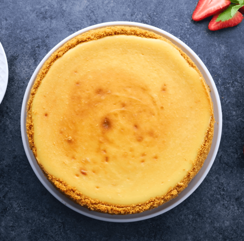 Overhead shot of a fully baked New York style cheesecake on a plate. 