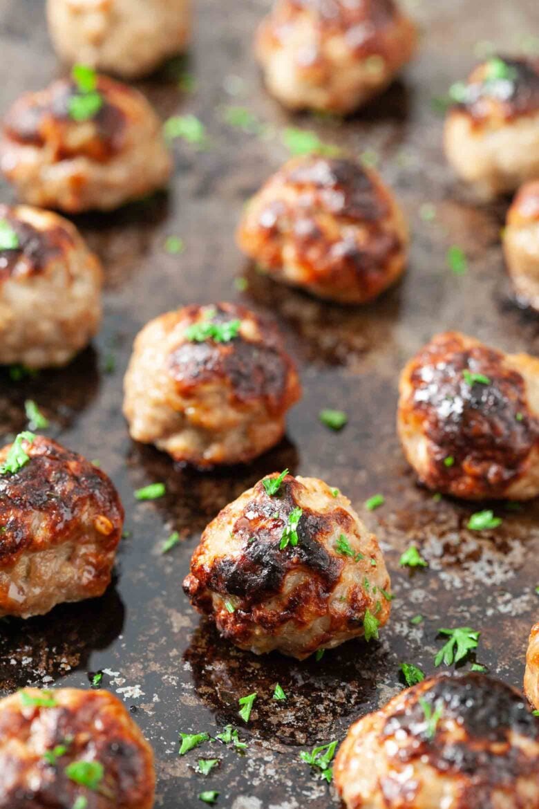 Overhead shot of Swedish meatballs in gravy in a skillet garnished with freshly chopped herbs.