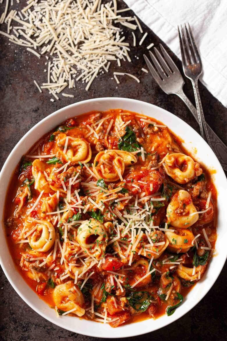 Overhead shot of Tuscan tortellini with sausage and spinach in a tomato based sauce.