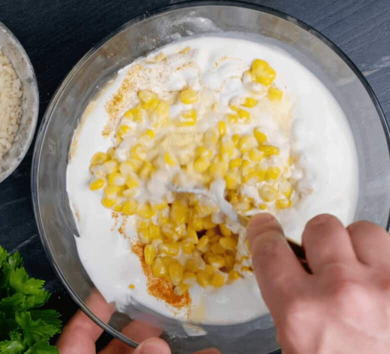 Easy corn casserole wet ingredients added to the dry ingredients in a large glass bowl.