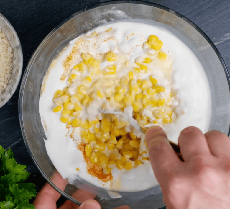 Easy corn casserole wet ingredients added to the dry ingredients in a large glass bowl.