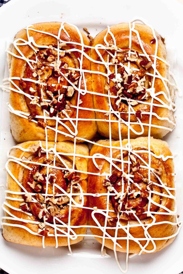 Overhead shot of cinnamon rolls with cream cheese frosting and chopped walnuts.