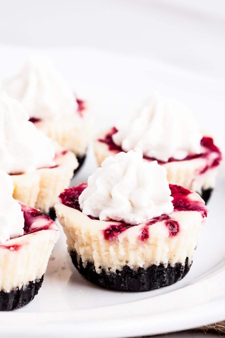 White chocolate raspberry cheesecakes with stabilized whipped cream.