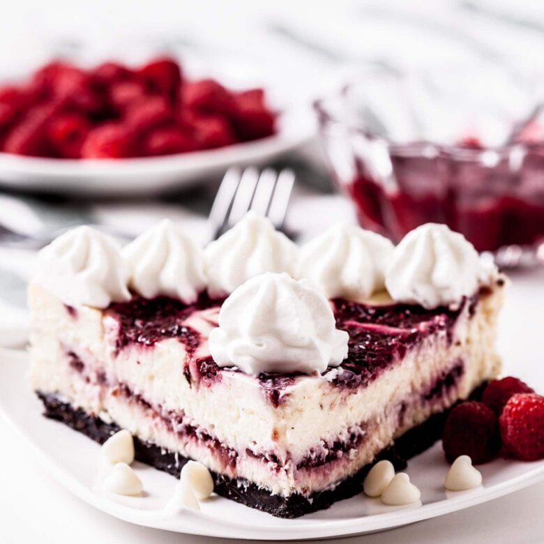 white chocolate raspberry cheesecake slice with whipped cream. 