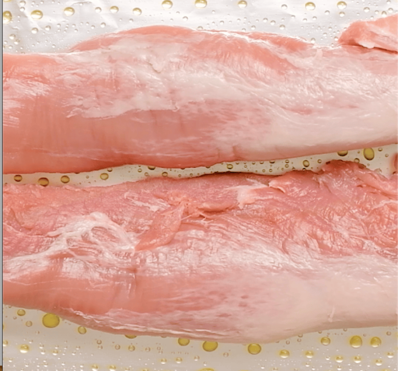 Pork tenderloin on a large, greased baking pan lined with foil.