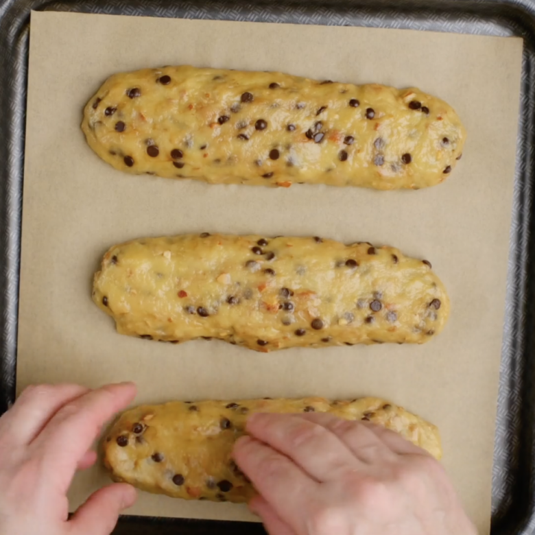 Three logs of almond biscotti dough on a baking sheet lined with parchment paper.