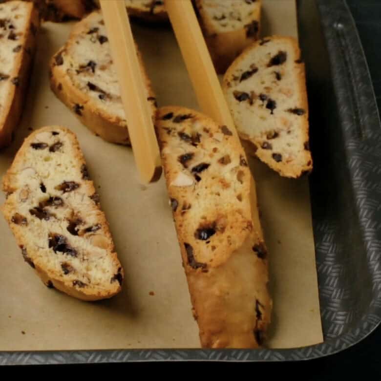 Almond biscotti being flipped halfway during second bake.