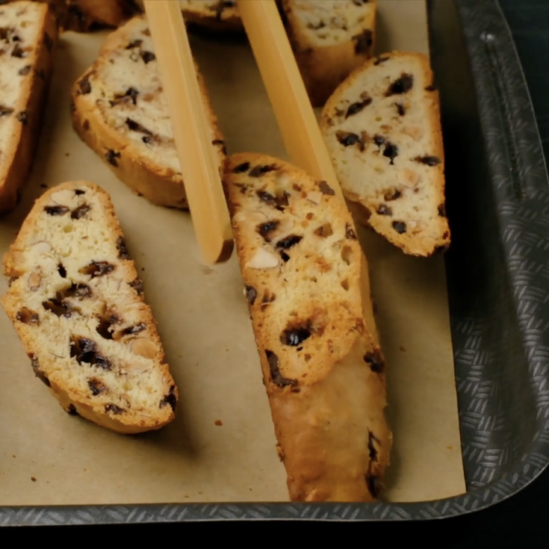 Almond biscotti being flipped halfway during second bake.