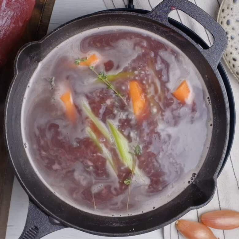 Red wine sauce for beef tenderloin being simmered in a pot.