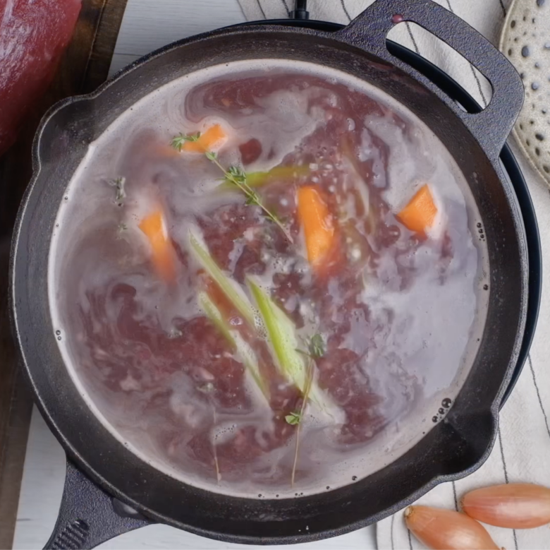 Red wine sauce for beef tenderloin being simmered in a pot. 