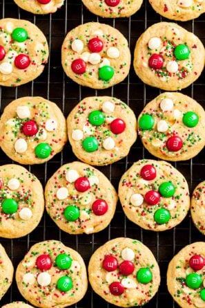 Overhead shot of M&M Christmas Cookies on a wire rack, featuring red and green M&Ms and sprinkles, and white chocolate chips.