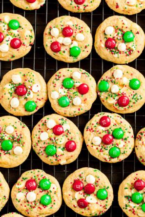 Overhead shot of M&M Christmas Cookies on a wire rack, featuring red and green M&Ms and sprinkles, and white chocolate chips.