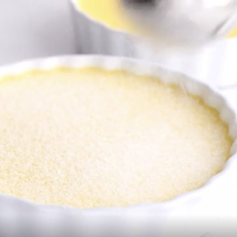 Sugar being sprinkled on top of baked creme brûlée.