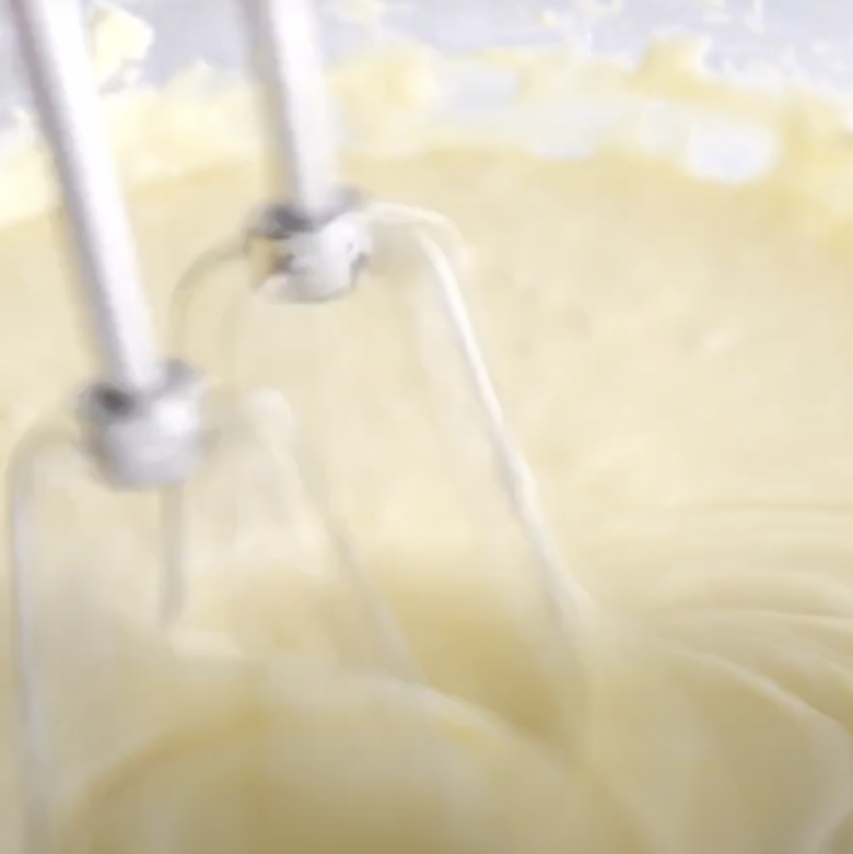 Cream mixture being mixed with an electric mixer for mini cheesecake.