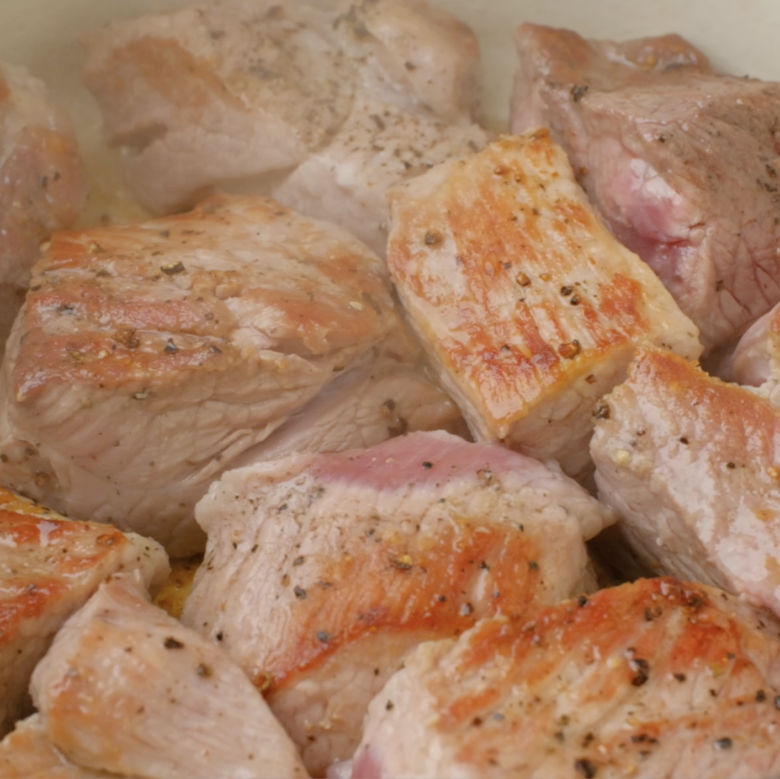 Pork being seared in a Dutch oven.