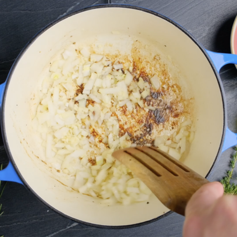 Onions and garlic being sauteed in a Dutch oven.