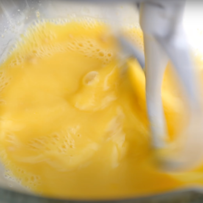 Water, yeast, sugar, and egg mixture being mixed in the bowl of a stand mixer to make cinnamon roll dough.