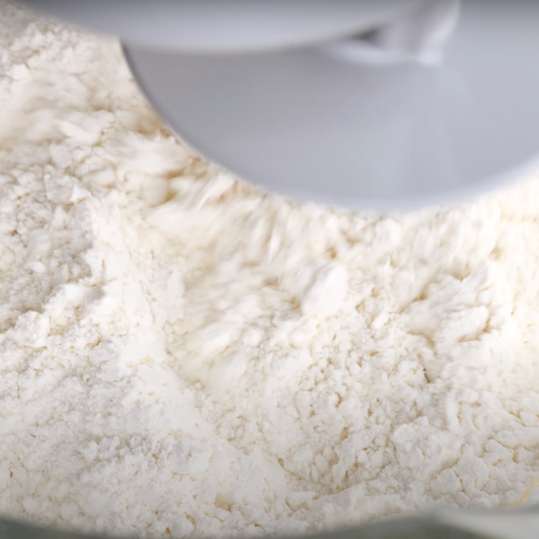 Flour mixture being mixed in a bowl of a stand mixer to make cinnamon roll dough.