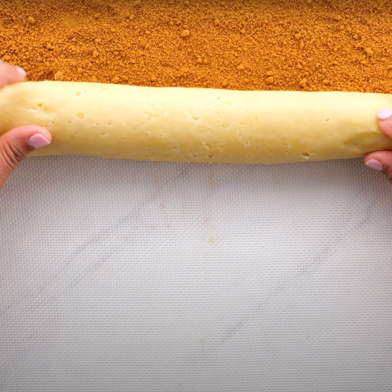 Cinnamon roll dough with cinnamon-sugar filling being rolled. 