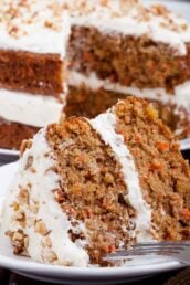 A slice of Carrot Cake With Cream Cheese Frosting on a white plate with a fork.