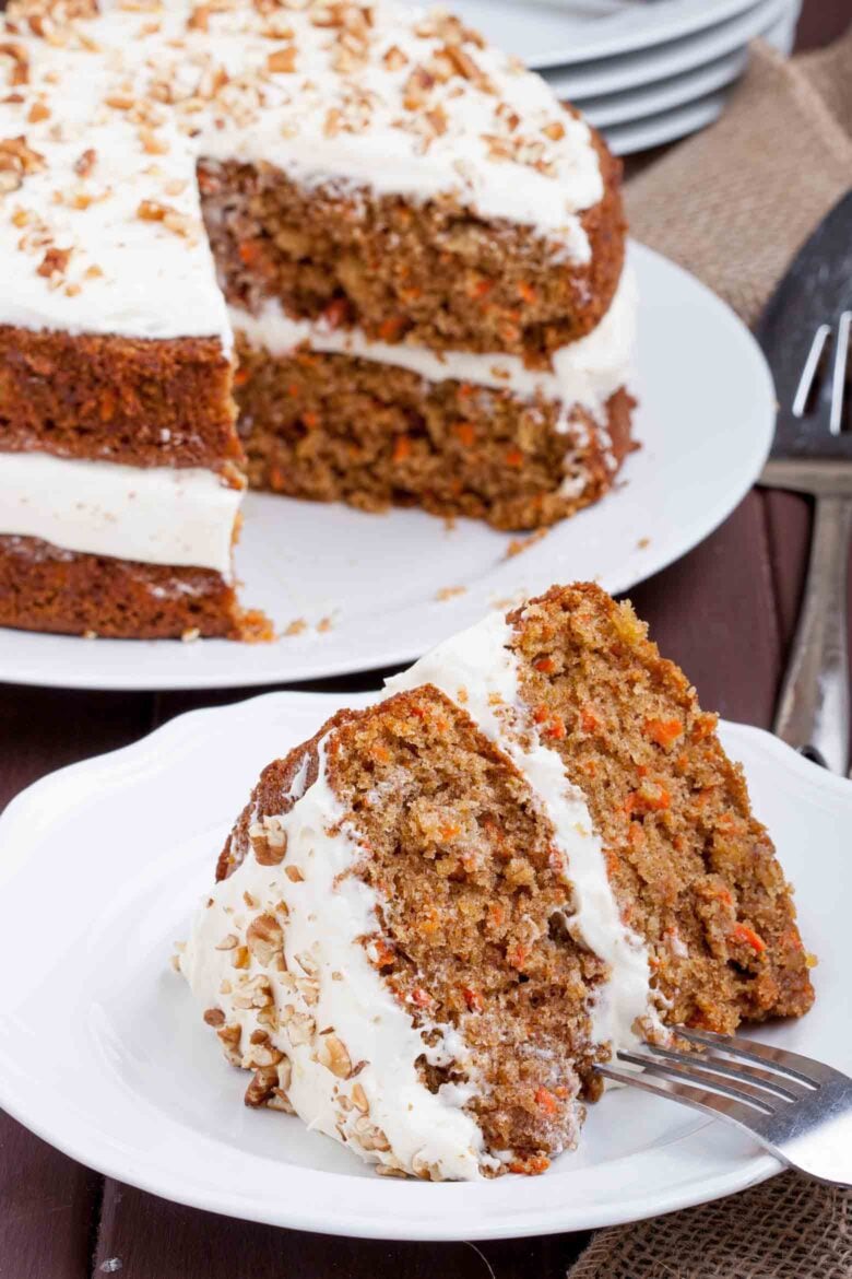 A slice of Carrot Cake With Cream Cheese Frosting on a white plate with a fork.