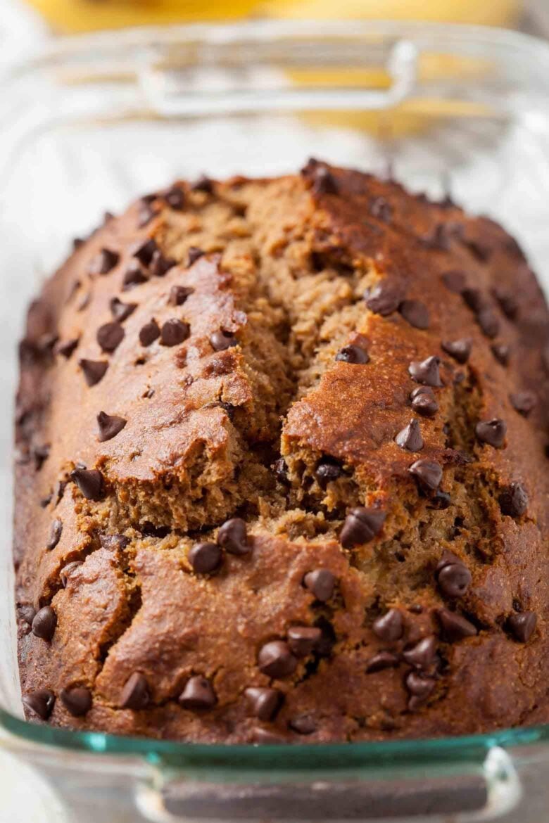 A loaf of dairy-free banana bread with chocolate chips in a glass baking dish.