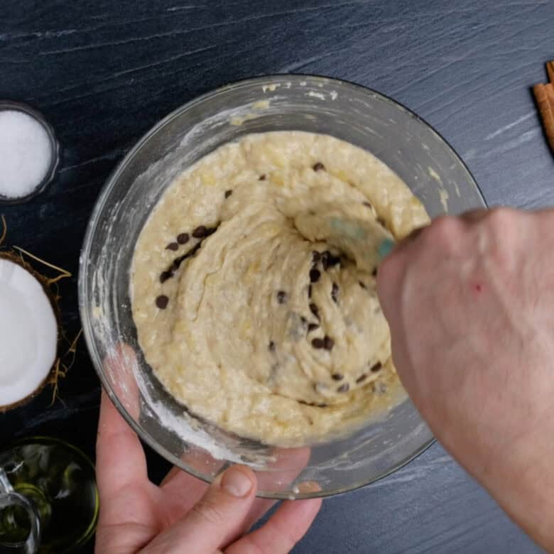 Flour and chocolate chips being folded in dairy-free banana bread batter.