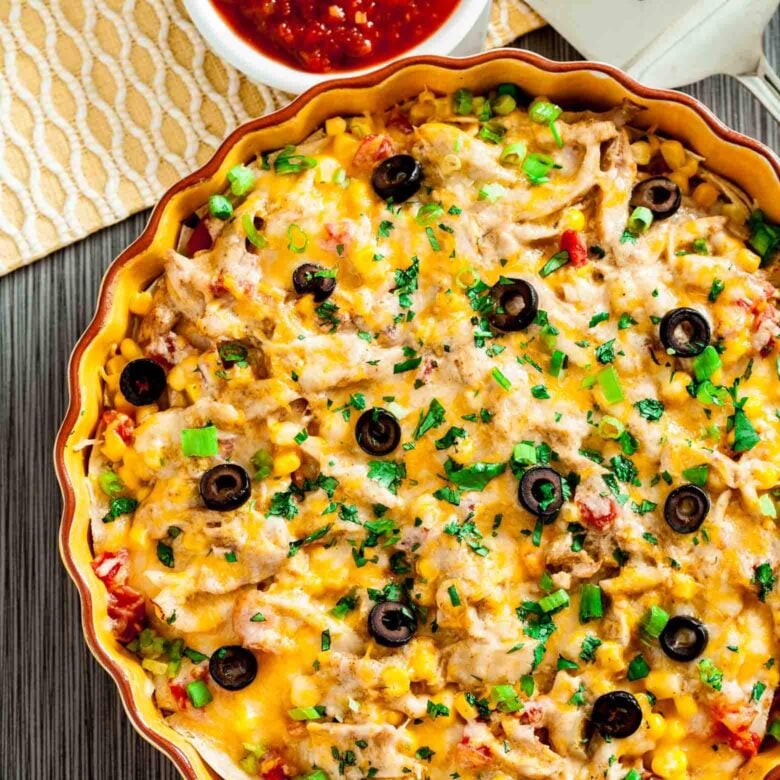 Freshly baked healthy chicken enchilada casserole garnished with chopped green onions and black olives.