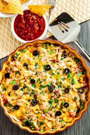 Freshly baked healthy chicken enchilada casserole with tortilla chips and salsa.