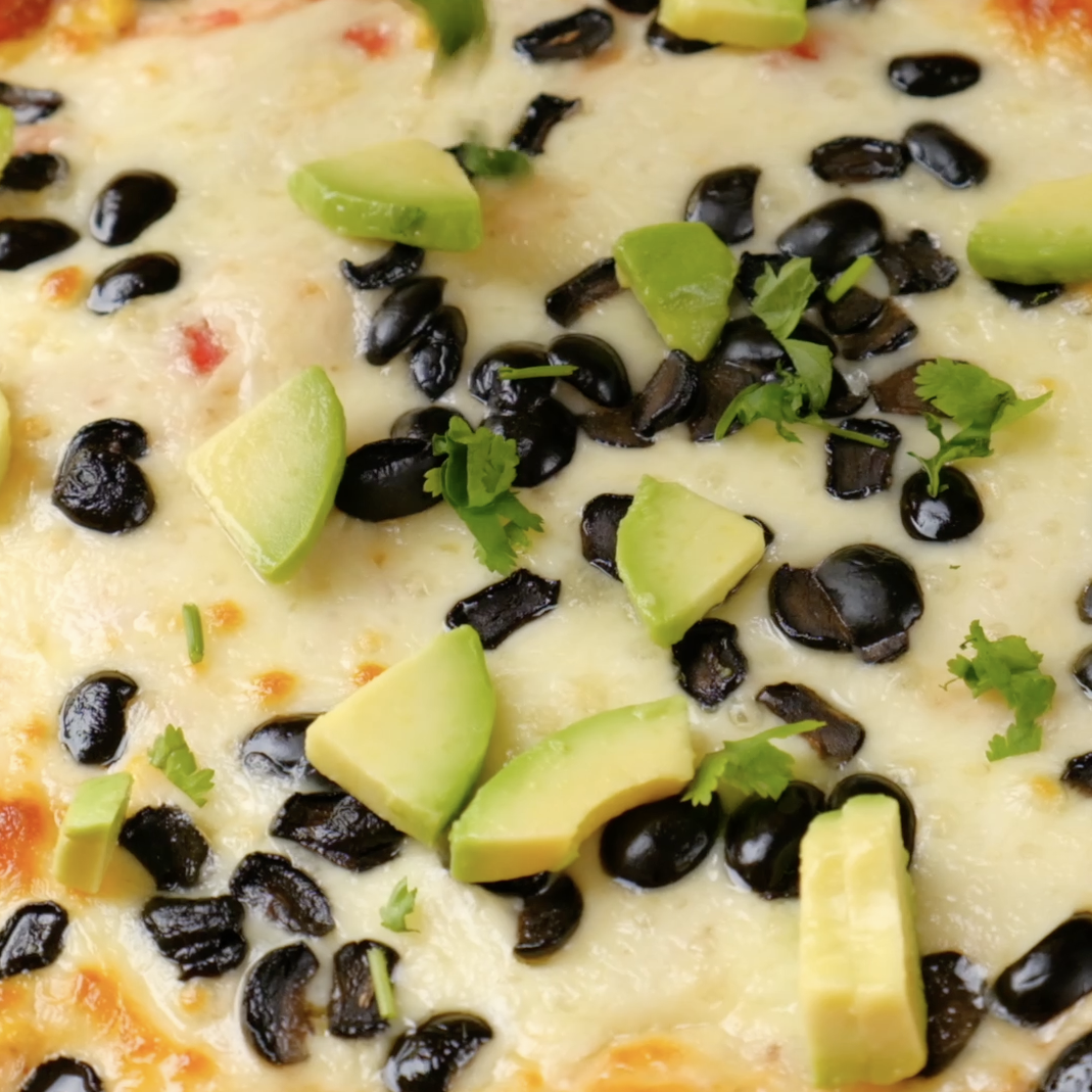Freshly baked healthy chicken enchilada casserole garnished with chopped avocados.