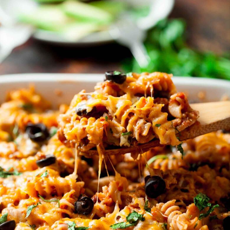 Closeup shot of a spoonful of Mexican pasta casserole in a white dish.