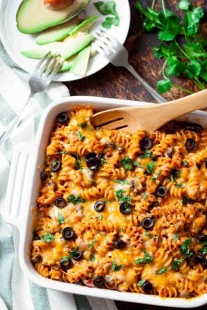 Mexican pasta bake in a casserole dish with a serving spoon.